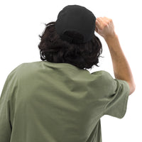 SNDT Essential Cap in black, angled side view showing snapback closure